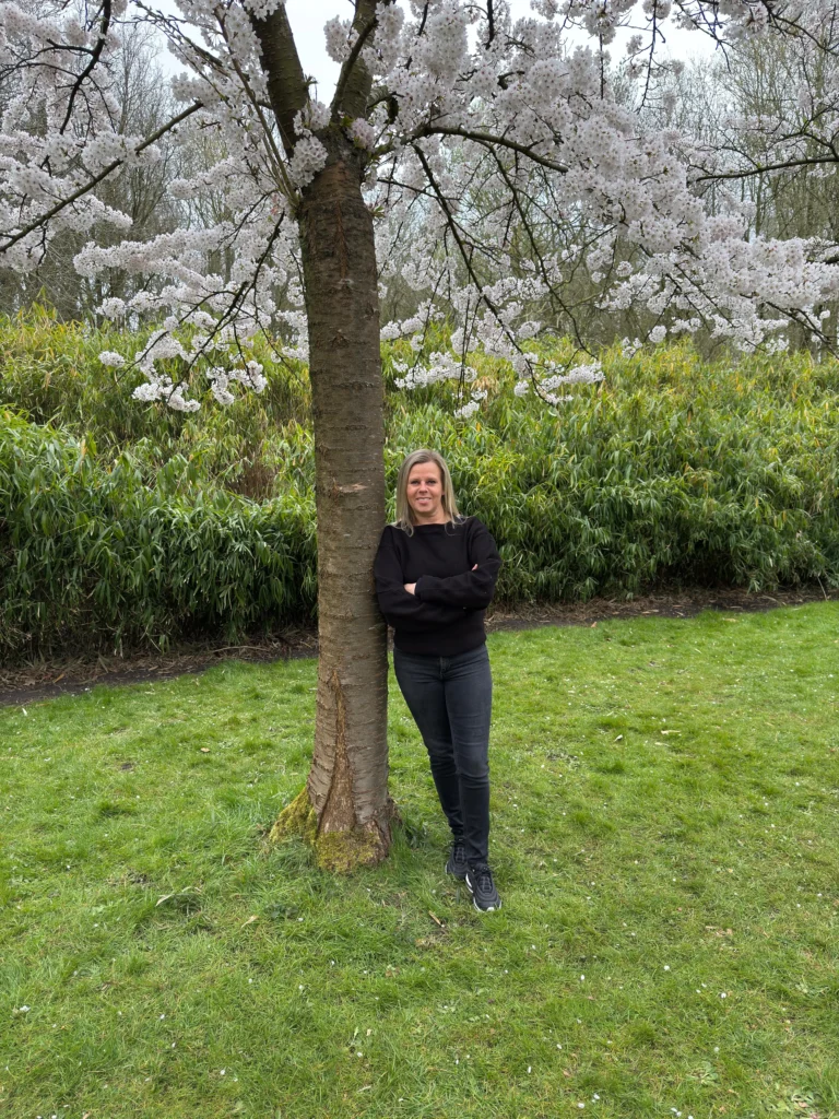 Marjolijn Kuijlenburg op een grasveld bij een bloesemboom